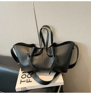 Détail d'un cabas noir en cuir avec sangles à double nœud et bandoulière réglable