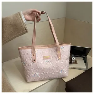 Detail of pink quilted tote bag with embroidered bows and monogram pattern