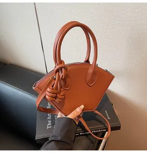 Détail du sac bandoulière en forme d'éventail avec poignées rondes et nœuds décoratifs