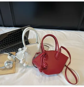 Détail des sacs à main forme coquille rouge et blanc avec décoration de poignée nouée