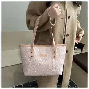 Close-up of pink tote bag featuring embossed E-pattern and colorful butterfly embroidery