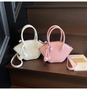 Vue détaillée de mini sacs coquillage en blanc et rose avec pendentifs noeuds en corde