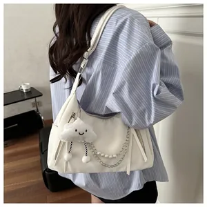 Detail of white half-moon bag with silver chain, pearls, and cute cloud plush pendant
