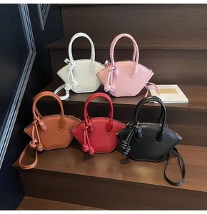 Détail de cinq sacs à main trapèze géométriques aux couleurs variées sur un escalier