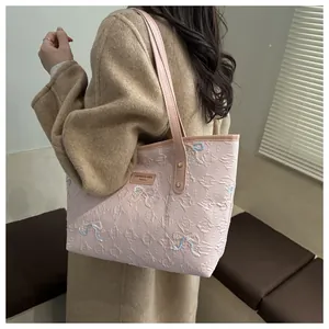 Detail of pink tote bag with embossed E pattern and colorful embroidered butterfly bows
