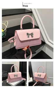 Detail of pink bow handbag featuring shiny sequins and metallic buckle on small square bag