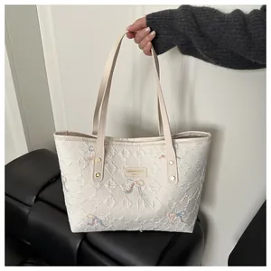 Detail of white quilted tote bag featuring butterfly embroidery and textured fabric