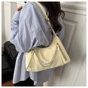 Detail of cream yellow shoulder bag featuring pearl metal chain and long tassel zipper