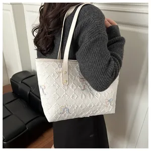Model view of a large white tote bag with quilted diamond pattern and colorful bows