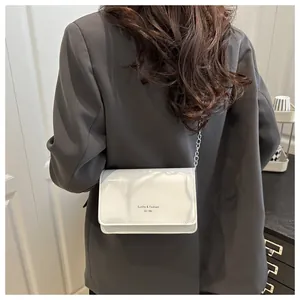 Achteraanzicht van model met witte PU-crossbodytas met ketting en grijze blazer