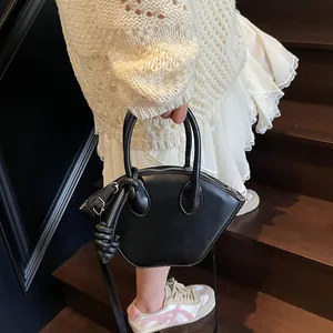 Sac à main noir en cuir forme coquille avec nœud porté par un mannequin en escalier