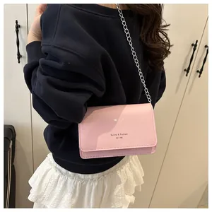 Detail van roze glanzende PU-crossbodytas met zilveren ketting en gedrukte letters
