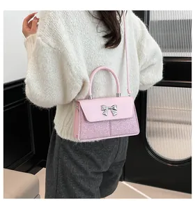 Detail of pink sequin handbag with silver bow charm and adjustable shoulder strap