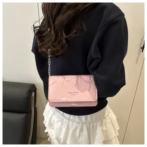 Roze glanzende crossbodytas met zilveren ketting getoond op een vrouwelijk model