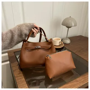 Conjunto de bolsos marrones en mesa de madera con estuche a juego y hebilla metálica