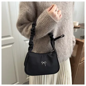 Détail du sac sous le bras noir avec nœud argenté et anse froncée élégante