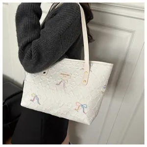 Quilted white tote bag with colorful bow embroidery and metallic brand logo detail