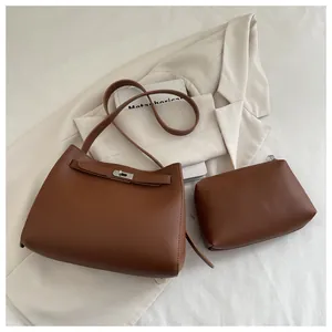 Detalle de conjunto de bolso bandolera de cuero marrón con cierre giratorio plateado