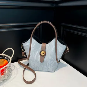 Grey textured bucket bag with brown leather straps and amber twist lock detail