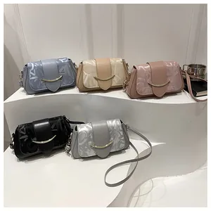 Close-up of five colorful textured flap crossbody bags with golden moon-shaped buckles