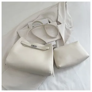 Vista detallada del conjunto de bolsos minimalistas blanco crudo con estuche y correa