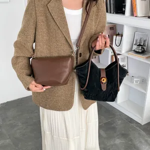 Brown leather bucket bag and black pleated handbag with circular handles on model