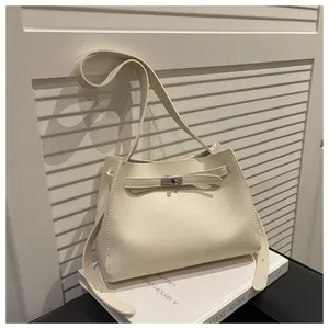 Detalle de bolso de cuero blanco crema con hebilla plateada sobre base de libro elegante