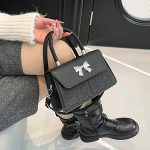 Fashionable black crossbody bag with glitter panels and a silver metal bow accent