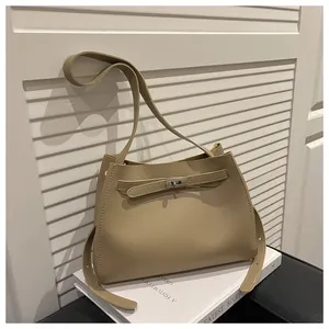 Detalle del bolso bandolera caqui claro con cierre de giro plateado y cuero liso