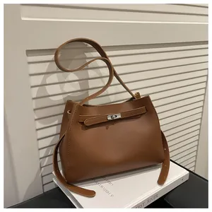 Detalle de bolso de cuero marrón caramelo con cierre giratorio plateado y costuras finas