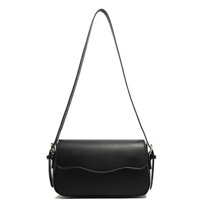 Chic black shoulder bag with gold hardware and wavy flap edge on white background