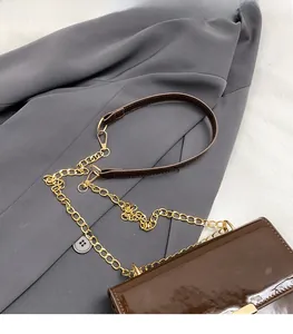 Detail of smooth dark brown patent leather crossbody bag with gold chain and leather strap