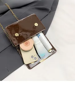 Detail view of brown patent leather crossbody bag showing interior space and accessories