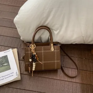 Braune gesteppte Umhängetasche mit Holzperlenquaste und elegantem Ledergriff