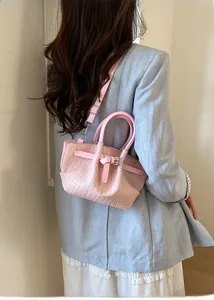 Detail of pink woven bucket bag with leather handles shown on a model's shoulder