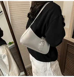 Close-up of metallic silver crescent shoulder bag featuring stylish belt buckle detail