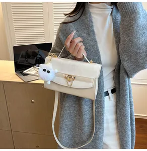 Détail du sac bandoulière crème avec boucle dorée et pompon blanc en peluche