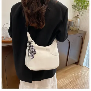 Détail du sac à bandoulière blanc en demi-lune avec pendentif à damier chic