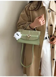 Détail du sac bandoulière vert clair avec fermoir cœur doré et breloque boule peluche