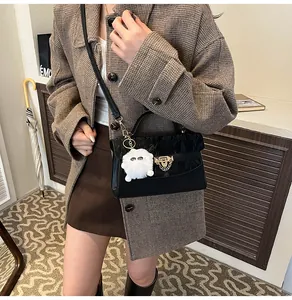 Détail d'un sac bandoulière noir matelassé avec fermoir doré et breloque en peluche