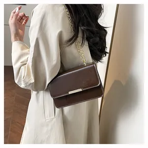 Detailed close-up of dark brown patent leather shoulder bag with a gold chain strap