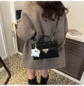 Gros plan détaillé d'un sac à main noir avec boucle dorée et breloque en peluche blanche