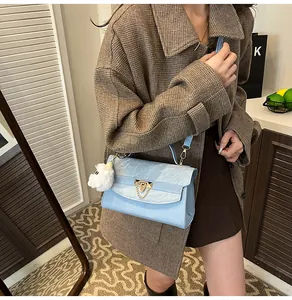 Détail du sac à main bleu clair avec fermoir triangle doré et breloque en peluche douce
