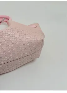 Detail shot of the reinforced thickened base of a pink woven bucket bag for shape retention