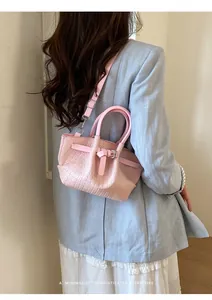 Pink woven bucket bag with buckle detail shown being worn with a blue blazer