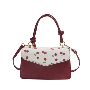 Red and white strawberry print crossbody bag with knotted handle and gold hardware detail