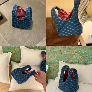 Detail der Denim-Einkaufstasche mit Schleifenmuster und rot-weiß kariertem Futter im Alltag