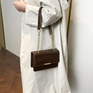 Brown patent leather shoulder bag with gold chain strap and sleek metal buckle design