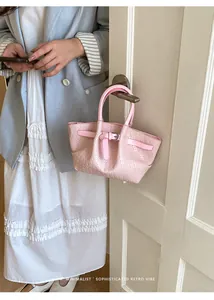Detail view of light pink woven bucket bag hanging on a door handle in a lifestyle setting