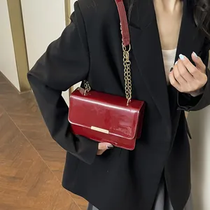 Burgundy patent leather crossbody bag with gold metallic trim and chain strap